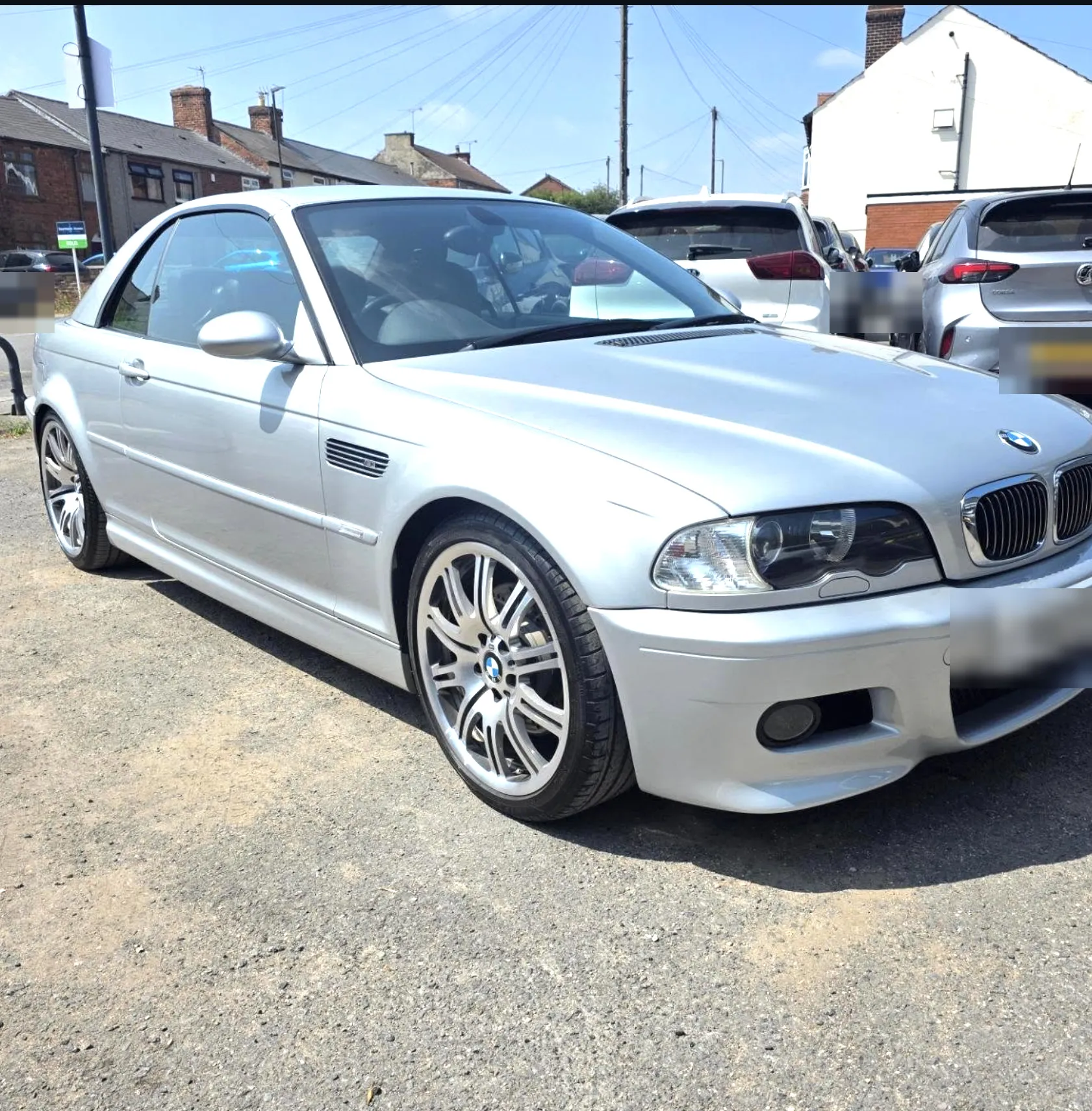 Silver BMW E46 M3 convertible with the roof up, parked in bright sunshine.